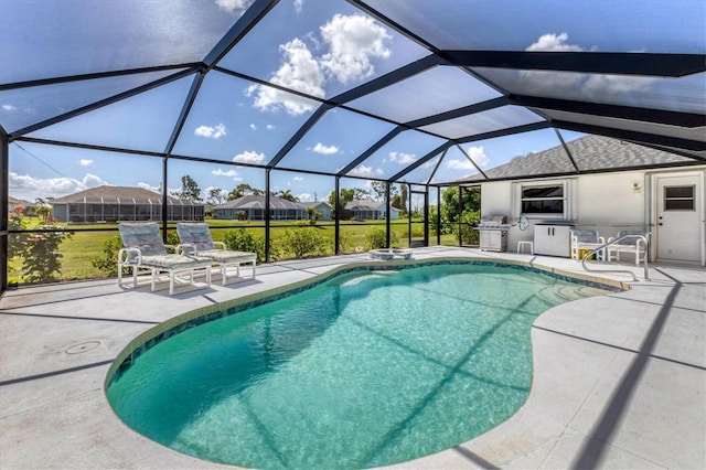 view of swimming pool featuring an outdoor kitchen, area for grilling, a patio area, and a lanai