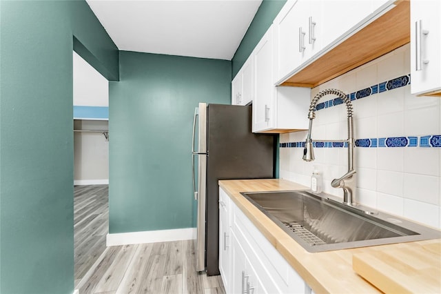 kitchen with backsplash, white cabinetry, sink, and light hardwood / wood-style flooring