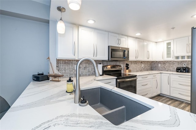 kitchen featuring white cabinetry, decorative light fixtures, decorative backsplash, appliances with stainless steel finishes, and dark wood-type flooring