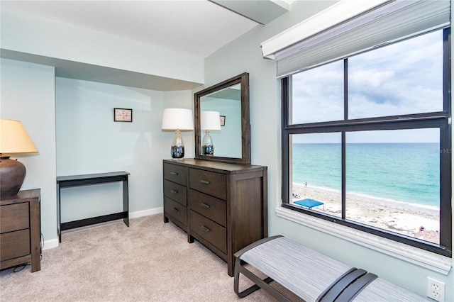 interior space with light carpet, a view of the beach, and a water view