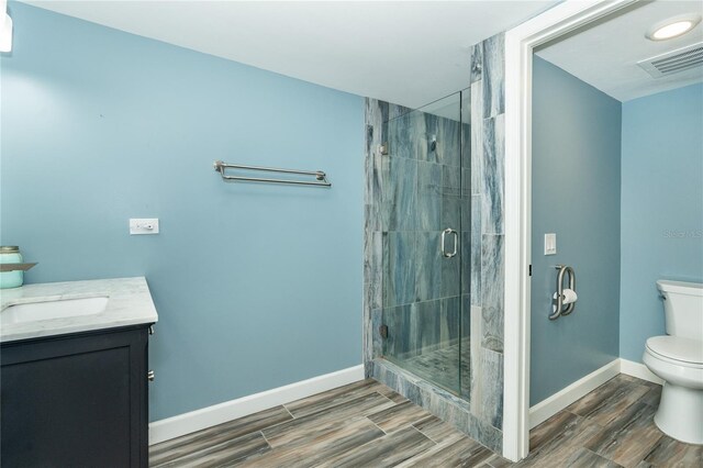 bathroom with a shower with door, toilet, and vanity