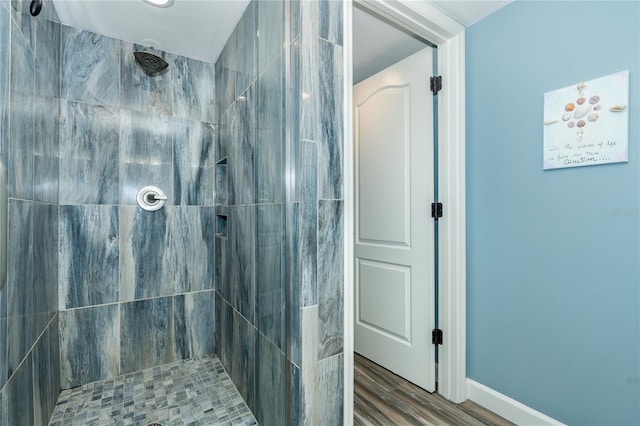 bathroom with tiled shower and wood-type flooring