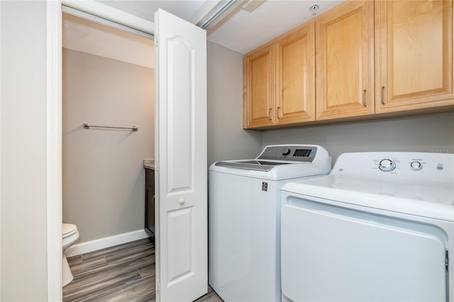 laundry area featuring dark wood-type flooring, washer and clothes dryer, and cabinets