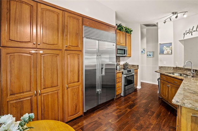 kitchen with light stone countertops, sink, stainless steel appliances, and dark hardwood / wood-style flooring