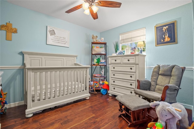 bedroom with ceiling fan, dark wood-type flooring, and a nursery area