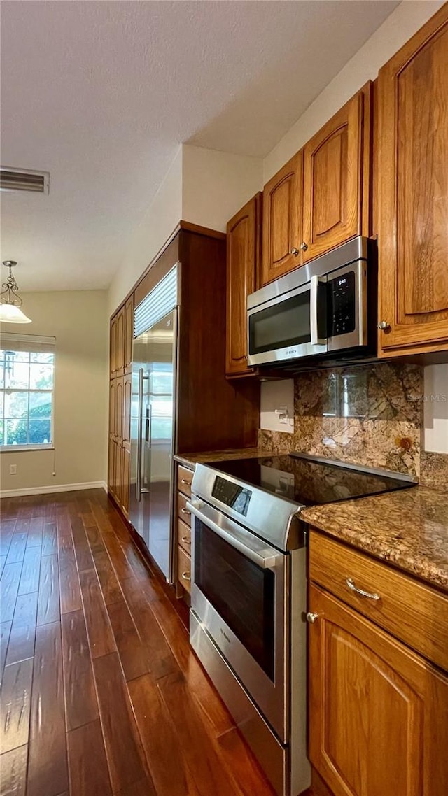 kitchen with stainless steel appliances, stone counters, dark wood-type flooring, and tasteful backsplash