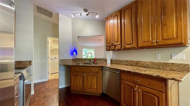 kitchen with appliances with stainless steel finishes, sink, dark hardwood / wood-style floors, and light stone counters