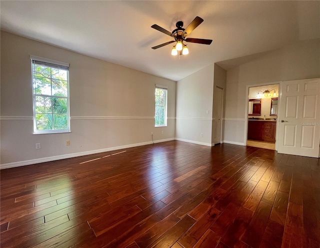 empty room with vaulted ceiling, dark wood-type flooring, ceiling fan, and a wealth of natural light