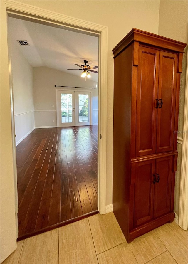 hallway with lofted ceiling, light hardwood / wood-style floors, and french doors