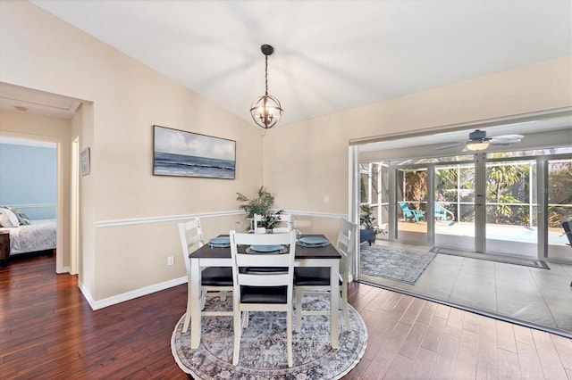 dining area featuring vaulted ceiling, ceiling fan with notable chandelier, wood finished floors, and baseboards