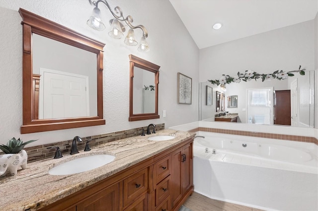 full bath with vaulted ceiling, a garden tub, a sink, and double vanity