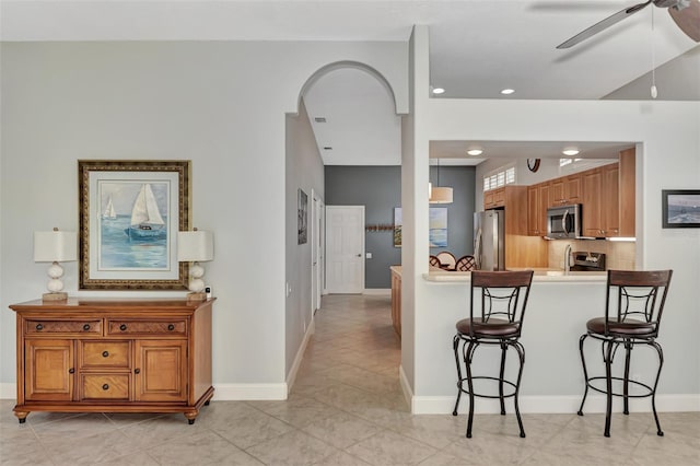 kitchen featuring a breakfast bar area, tasteful backsplash, decorative light fixtures, appliances with stainless steel finishes, and ceiling fan