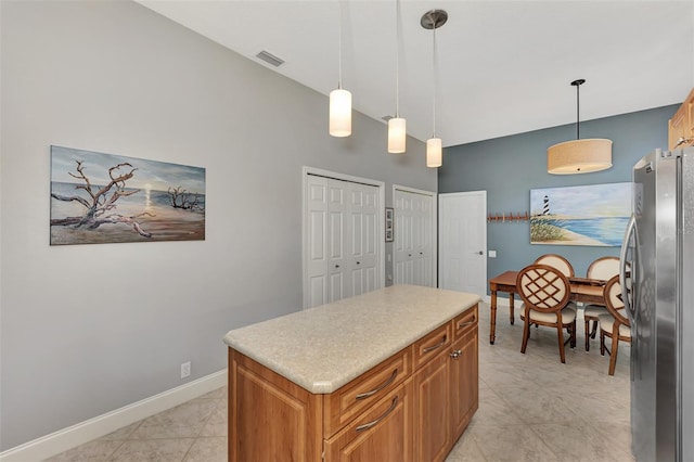 kitchen featuring hanging light fixtures, a kitchen island, light tile patterned floors, and stainless steel refrigerator