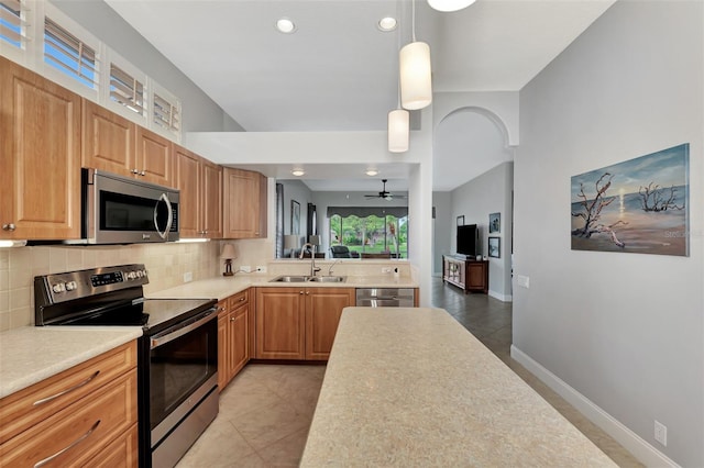 kitchen with decorative light fixtures, sink, decorative backsplash, light tile patterned floors, and stainless steel appliances