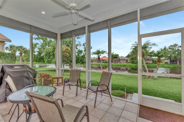 sunroom / solarium featuring a water view and ceiling fan