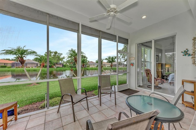 sunroom featuring ceiling fan and a water view