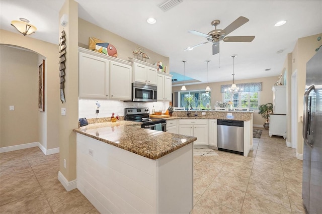 kitchen featuring decorative light fixtures, white cabinetry, appliances with stainless steel finishes, and kitchen peninsula