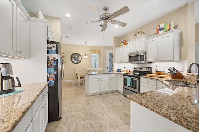 kitchen with pendant lighting, white cabinets, stainless steel appliances, sink, and kitchen peninsula