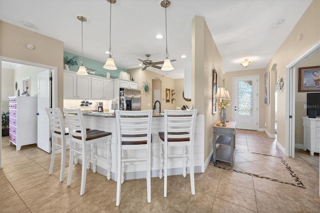 kitchen with a kitchen breakfast bar, decorative light fixtures, white cabinetry, stainless steel fridge with ice dispenser, and light tile patterned floors