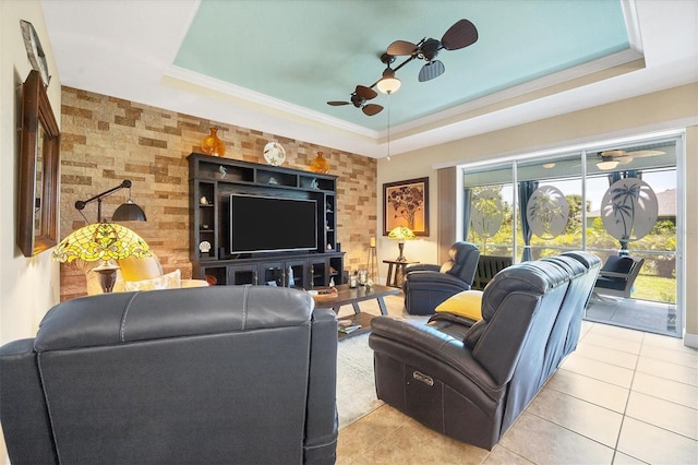 tiled living room with crown molding, ceiling fan, and a raised ceiling