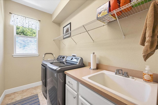 clothes washing area featuring cabinets, sink, and washer and clothes dryer