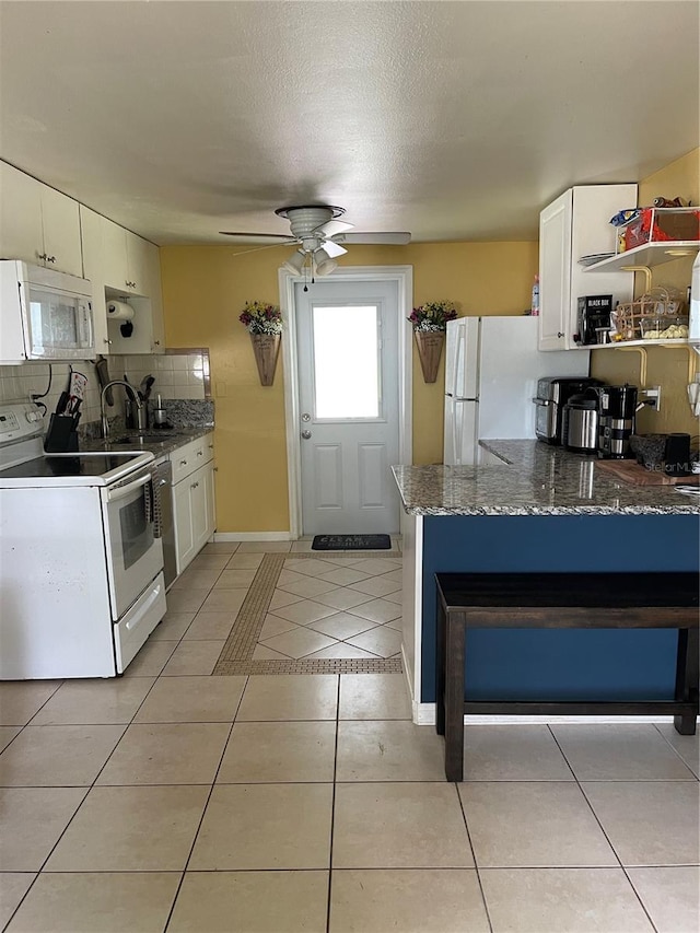 kitchen with tasteful backsplash, white appliances, light tile patterned floors, white cabinets, and ceiling fan