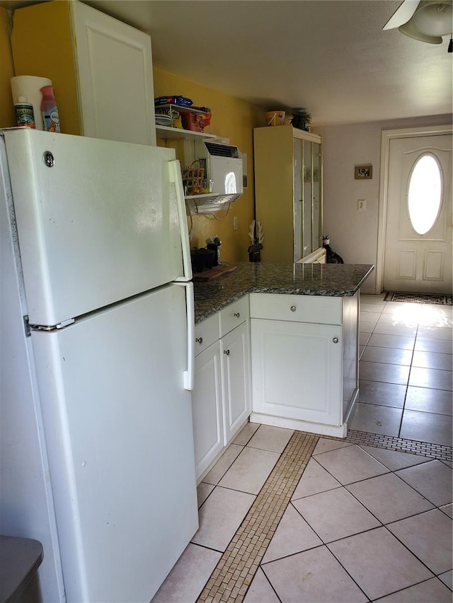 kitchen featuring dark stone counters, white cabinetry, white refrigerator, ceiling fan, and light tile patterned floors