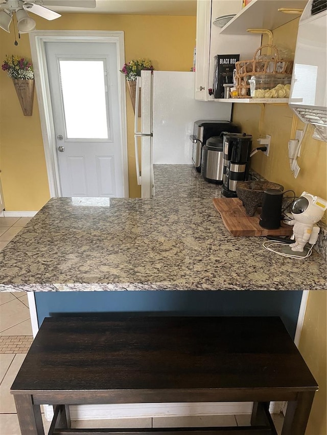 kitchen with white cabinets, white refrigerator, light tile patterned floors, and ceiling fan