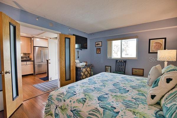 bedroom featuring light wood-type flooring and stainless steel refrigerator