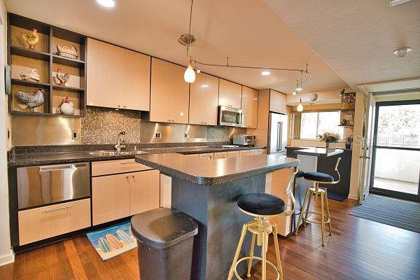 kitchen featuring decorative backsplash, pendant lighting, sink, a kitchen island, and dark wood-type flooring