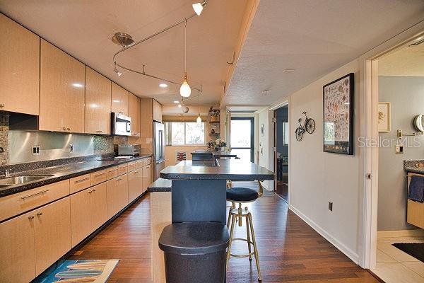 kitchen with pendant lighting, a kitchen breakfast bar, dark hardwood / wood-style flooring, and stainless steel appliances