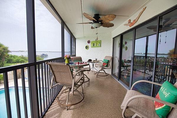 sunroom / solarium featuring a water view and ceiling fan