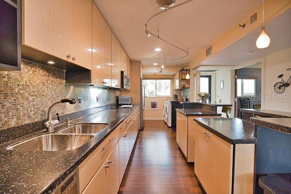 kitchen with sink, appliances with stainless steel finishes, plenty of natural light, and dark hardwood / wood-style floors