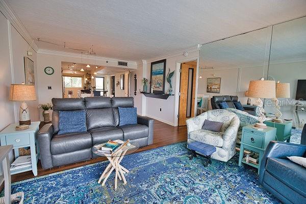 living room featuring ornamental molding, a textured ceiling, and hardwood / wood-style flooring