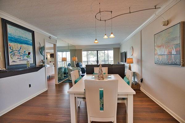 dining space featuring dark wood-type flooring, a textured ceiling, and ornamental molding