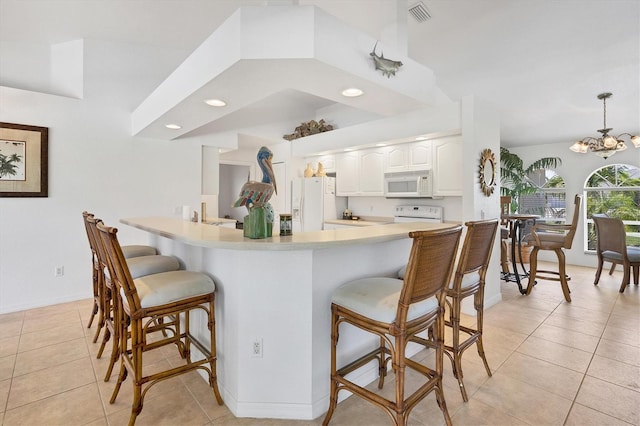 kitchen featuring decorative light fixtures, white appliances, white cabinetry, a breakfast bar area, and light tile patterned floors