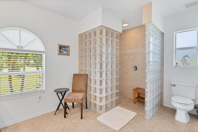 bathroom featuring tile patterned floors, tiled shower, and toilet