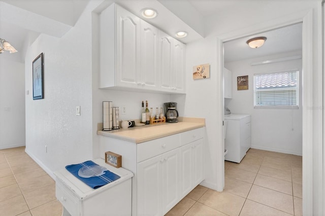 interior space featuring light tile patterned flooring, white cabinetry, and washing machine and clothes dryer