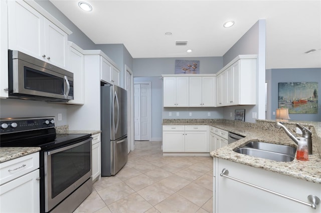 kitchen featuring light stone counters, sink, appliances with stainless steel finishes, and white cabinetry