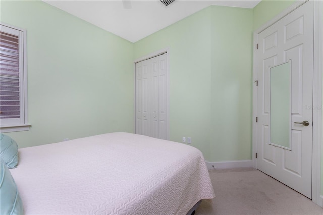 bedroom with light colored carpet, ceiling fan, and a closet