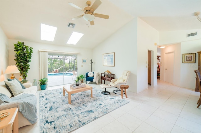 tiled living room with ceiling fan and vaulted ceiling with skylight