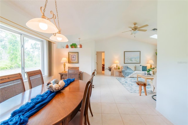 tiled dining area with vaulted ceiling with skylight and ceiling fan