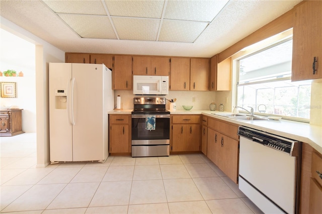 kitchen with light tile patterned flooring, sink, and white appliances