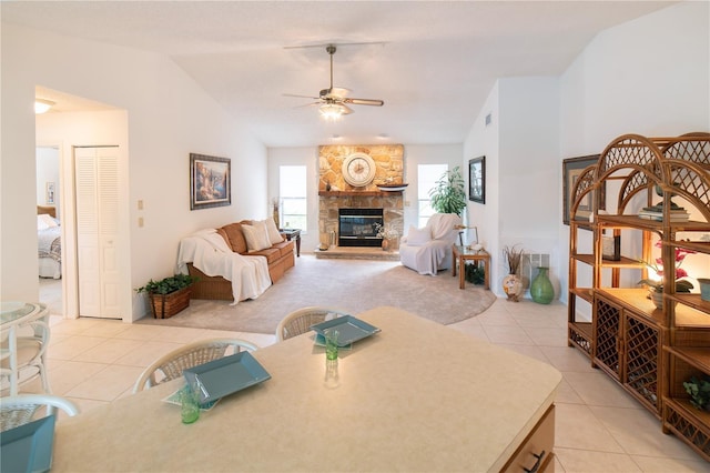 tiled living room with ceiling fan, lofted ceiling, and a fireplace