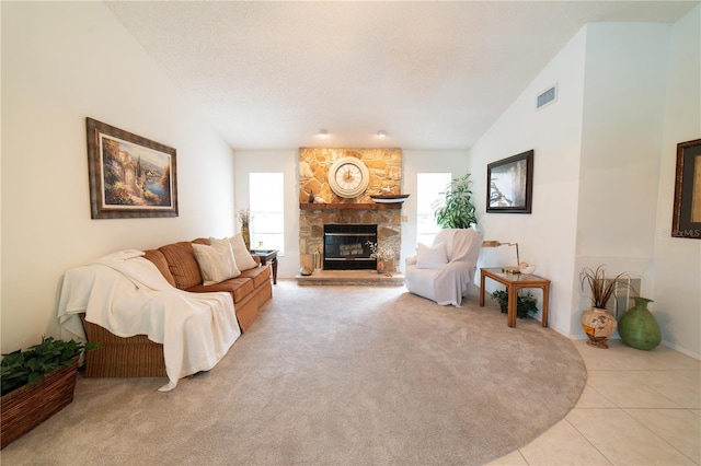 tiled living room with lofted ceiling, a stone fireplace, and a textured ceiling