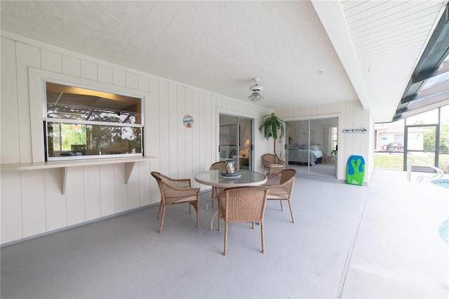 view of patio with ceiling fan and glass enclosure