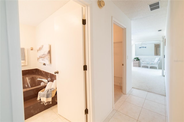 bathroom with a bathing tub, tile patterned flooring, and a textured ceiling