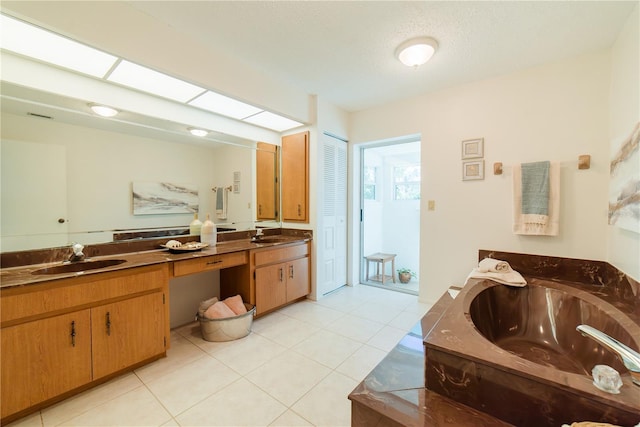 bathroom featuring tile patterned floors, a skylight, a textured ceiling, vanity, and a bath