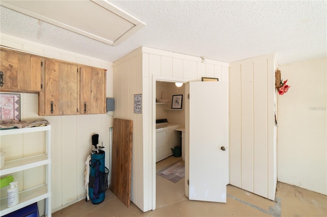 interior space with washer and dryer, a textured ceiling, and wood walls