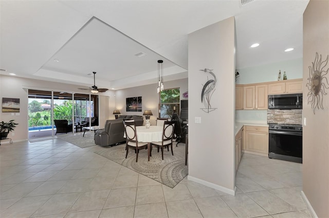 interior space with ceiling fan, light tile patterned floors, appliances with stainless steel finishes, and a tray ceiling